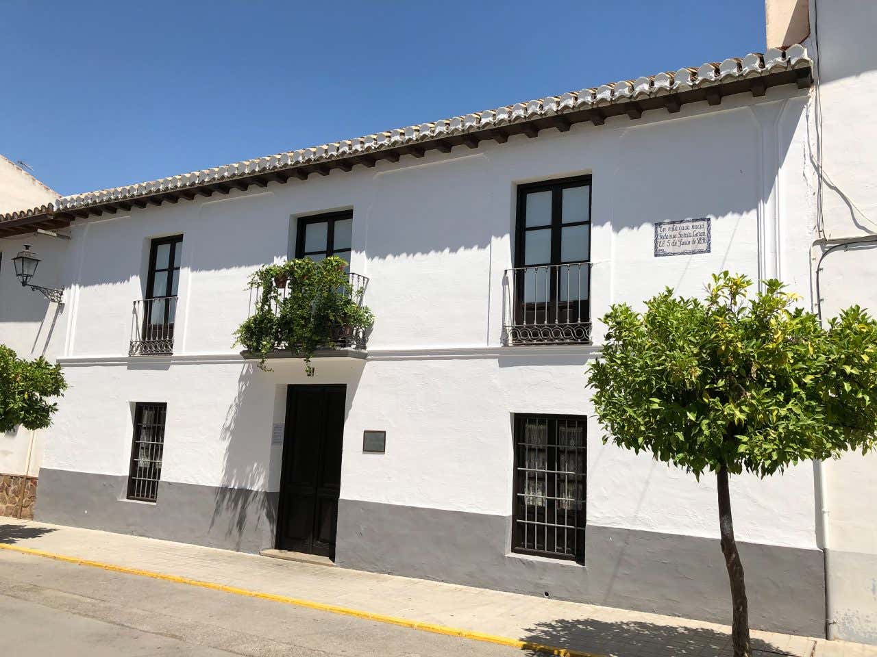 Una casa ottocentesca di colore bianco a due piani. Al primo piano la porta d'ingresso e due finestre laterali, al secondo pianto tre finestre con balconi decorati con piante e una targa che riporta la nascita di Francisco García Lorca il 5 giugno 1898