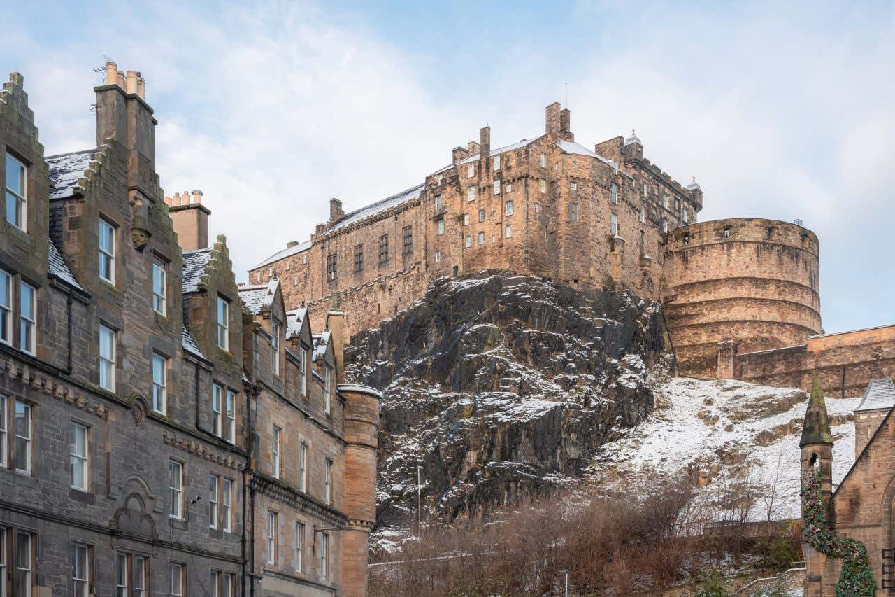 Il castello di Edimburgo fotografato dal basso, ricoperto di neve e abbarbicato in cima a una roccia