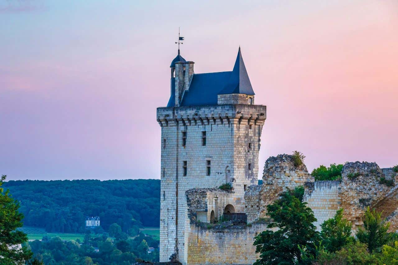 Château d'Angers in the foreground with a pink and purple sky in the background.