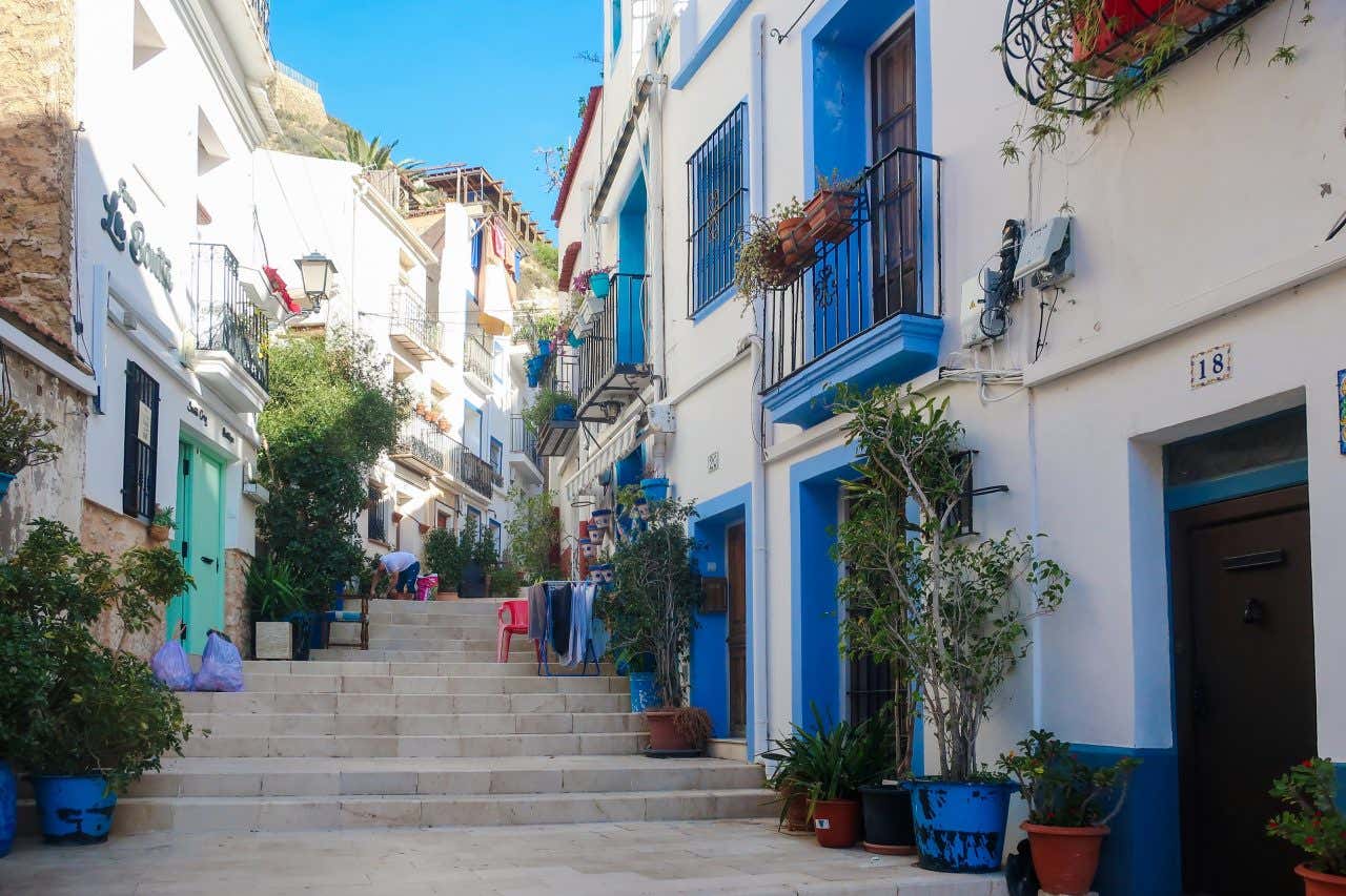 Una stradina tipica del quartiere di Santa Cruz, con una scalinata circondata da case passe di colore bianco e blu e decorati con vasi e piante