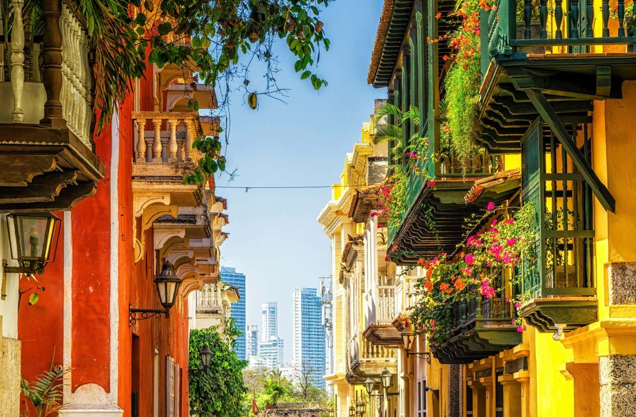 Bâtiments rouge et jaune, balcons ornés de plantes et gratte-ciel au loin à Carthagène, en Colombie