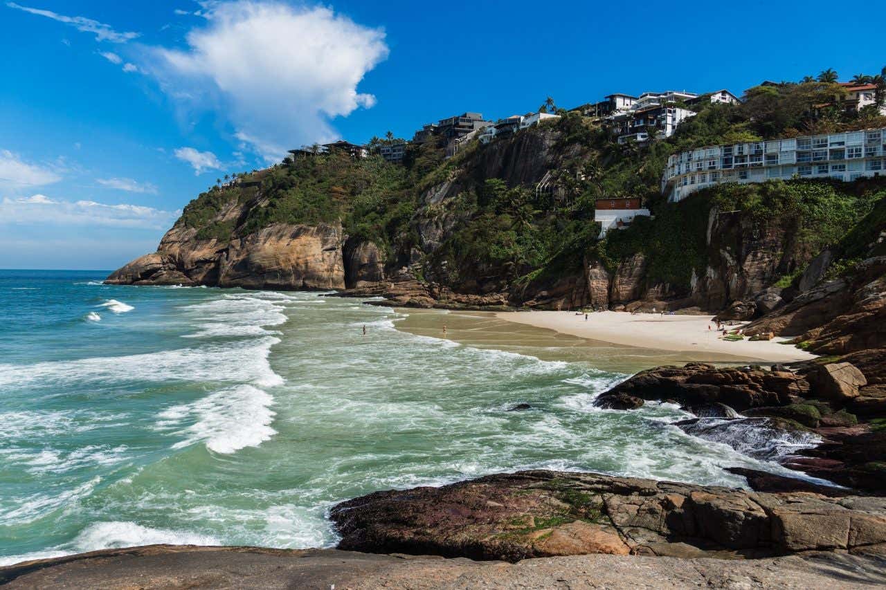 Mar verde-esmeralda com boas ondas cercadas de montanhas e colinas ao redor e muita natureza