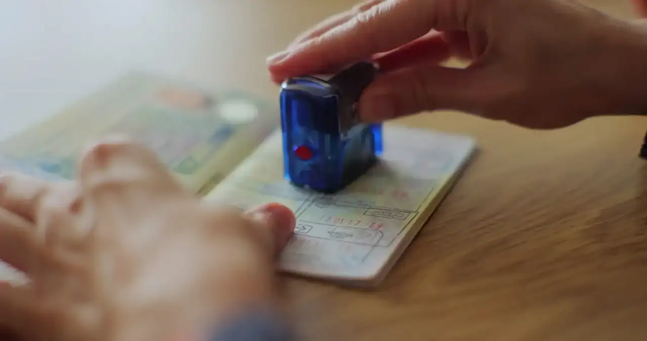 Detalhe de uma mão carimbando um passaporte