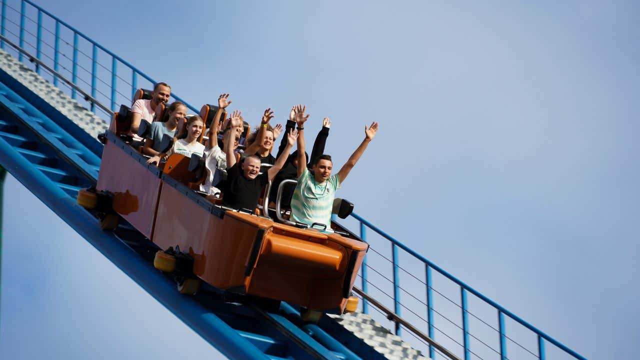 A rollercoaster with riders having a good time, some with their hands in the air.