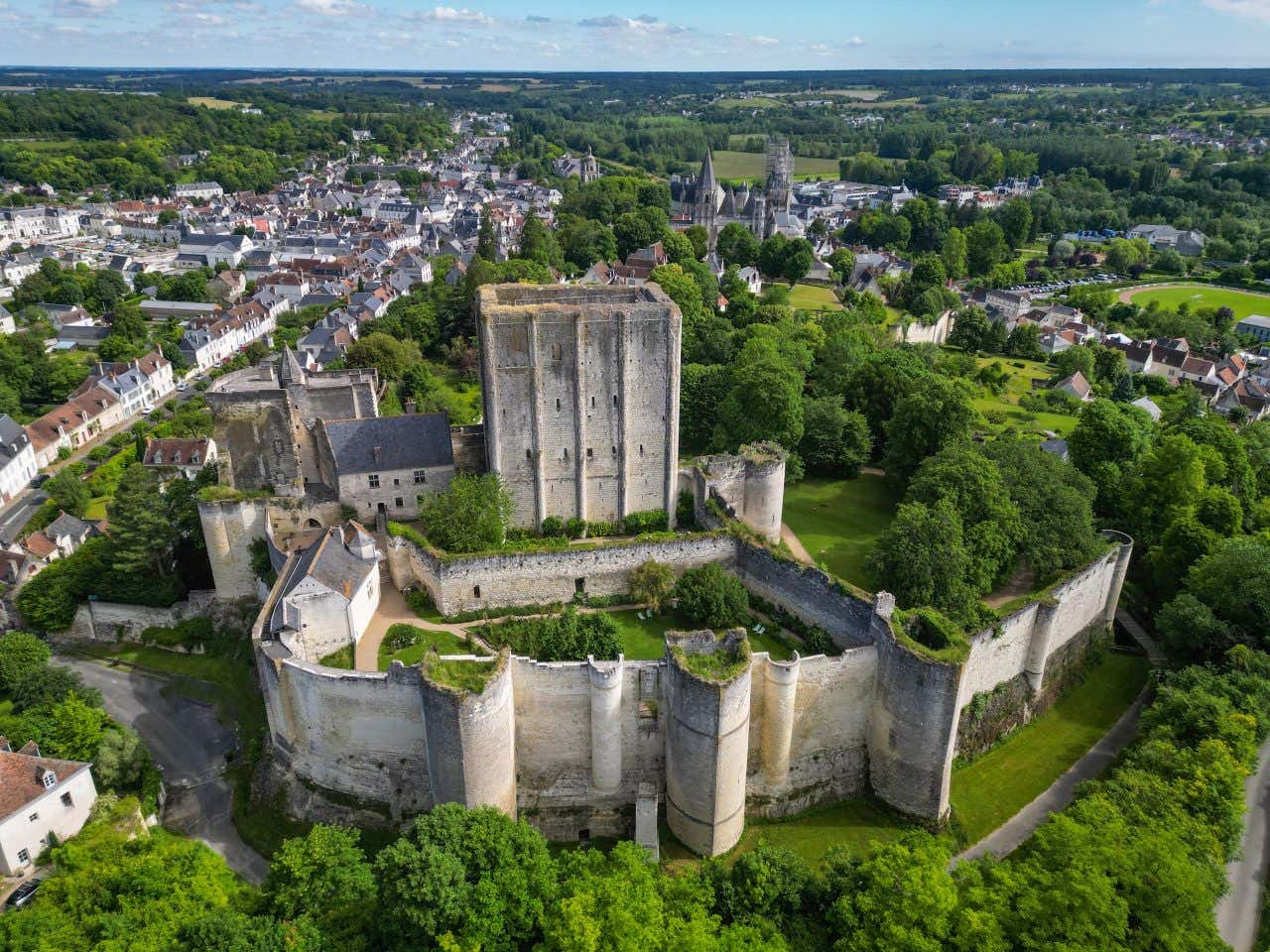 An aerial view of the Château de Loches with a town in the background and various trees surrounding it.