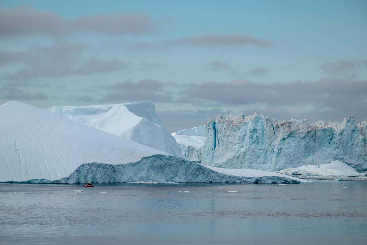 A shot of Vostok Lake in Antarctica, with various glaciers in the background and a small boat at the front.