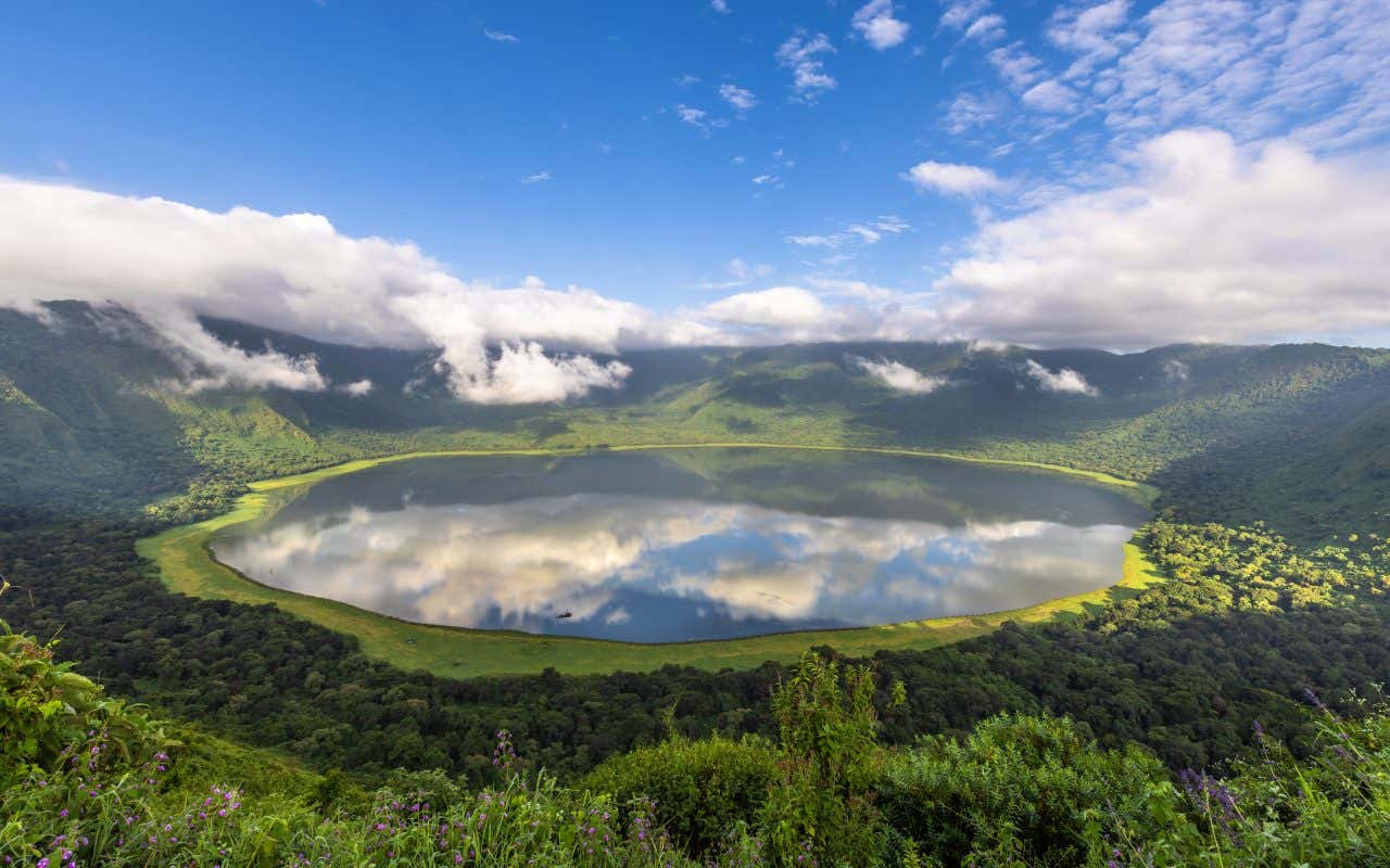 Cratère du Ngorongoro, avec le reflet du ciel dans l'eau du cratère et de la végétation verdoyante autour