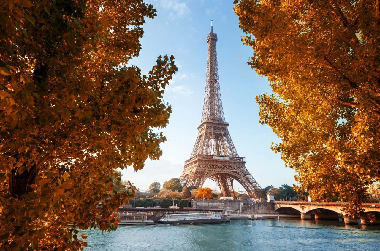 Panorâmica da Torre Eiffel ladeada por árvores de folhas douradas do outono
