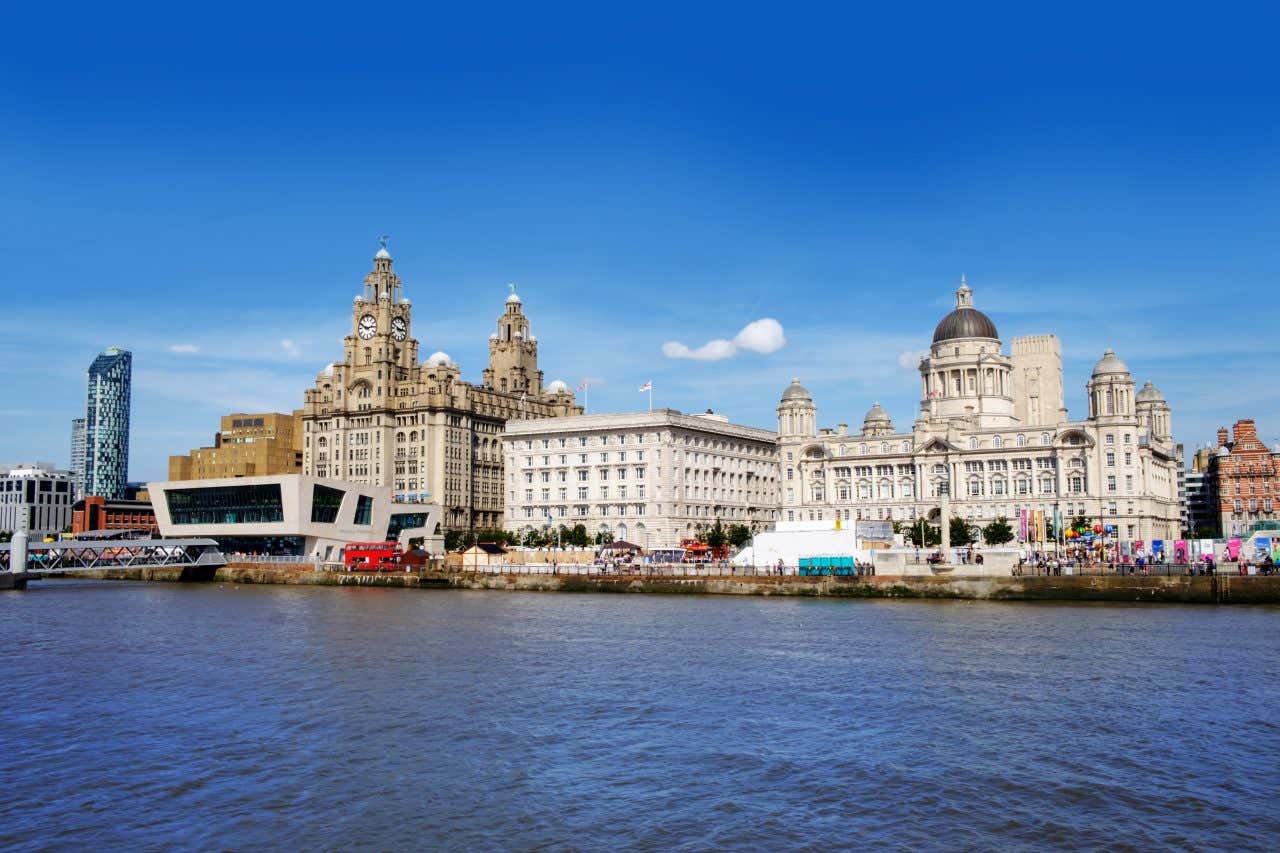 A wide shot of the Mersey River with old buildings and a mostly clear blue sky in the background.
