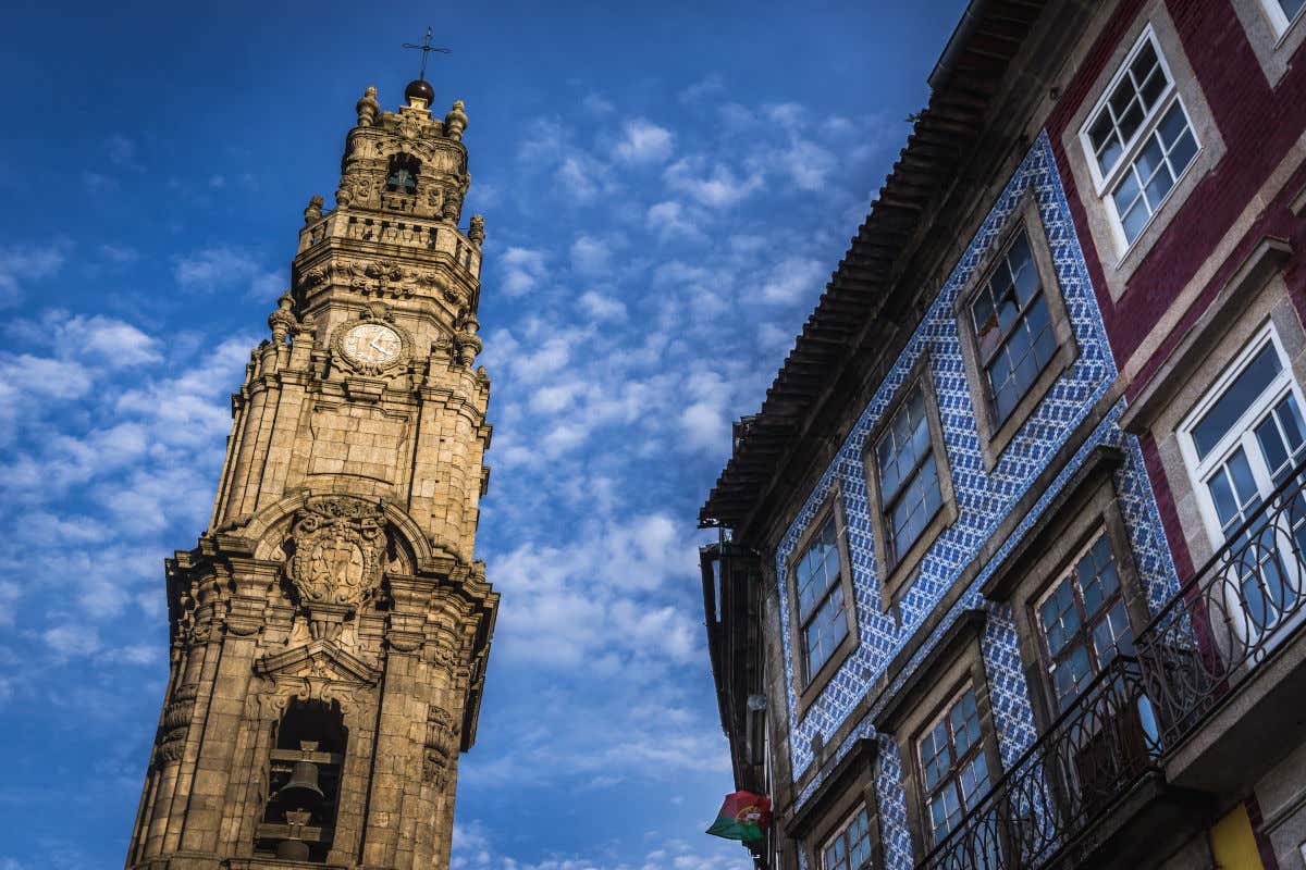 Una torre del reloj con varias decoraciones de piedra y una campana junto a varias casas portuguesas