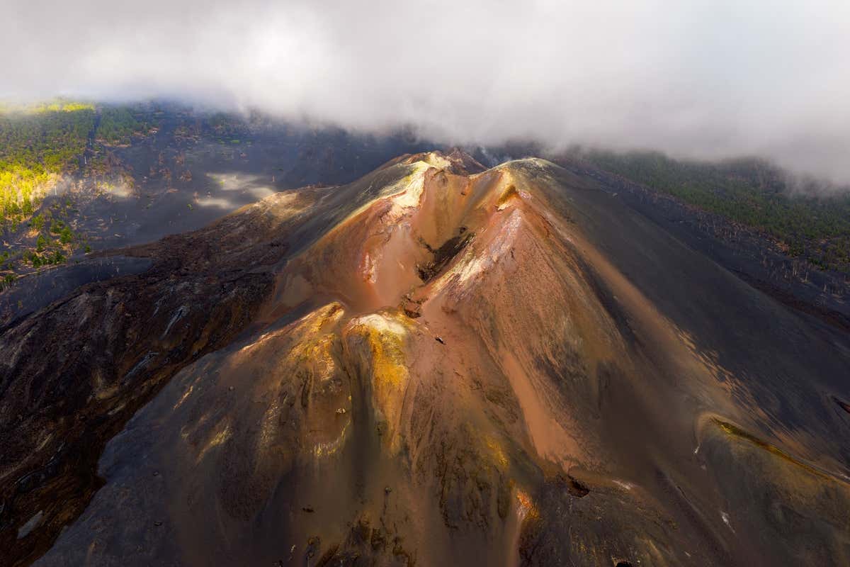 Vista aérea del volcán de Tajogaite rodeado de nubes, el ejemplo más reciente de erupciones en La Palma
