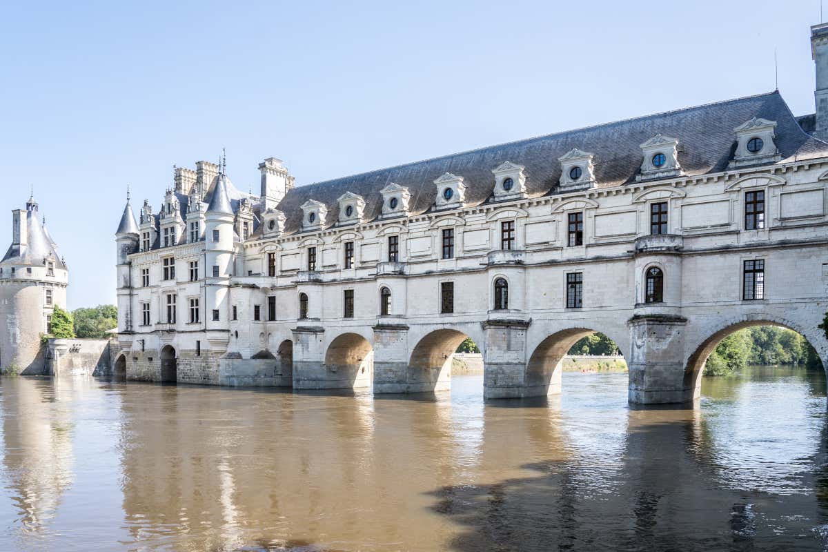 Vista de un castillo, en cuya parte inferior hay unos arcos que cruzan un río, como si fuera un puente