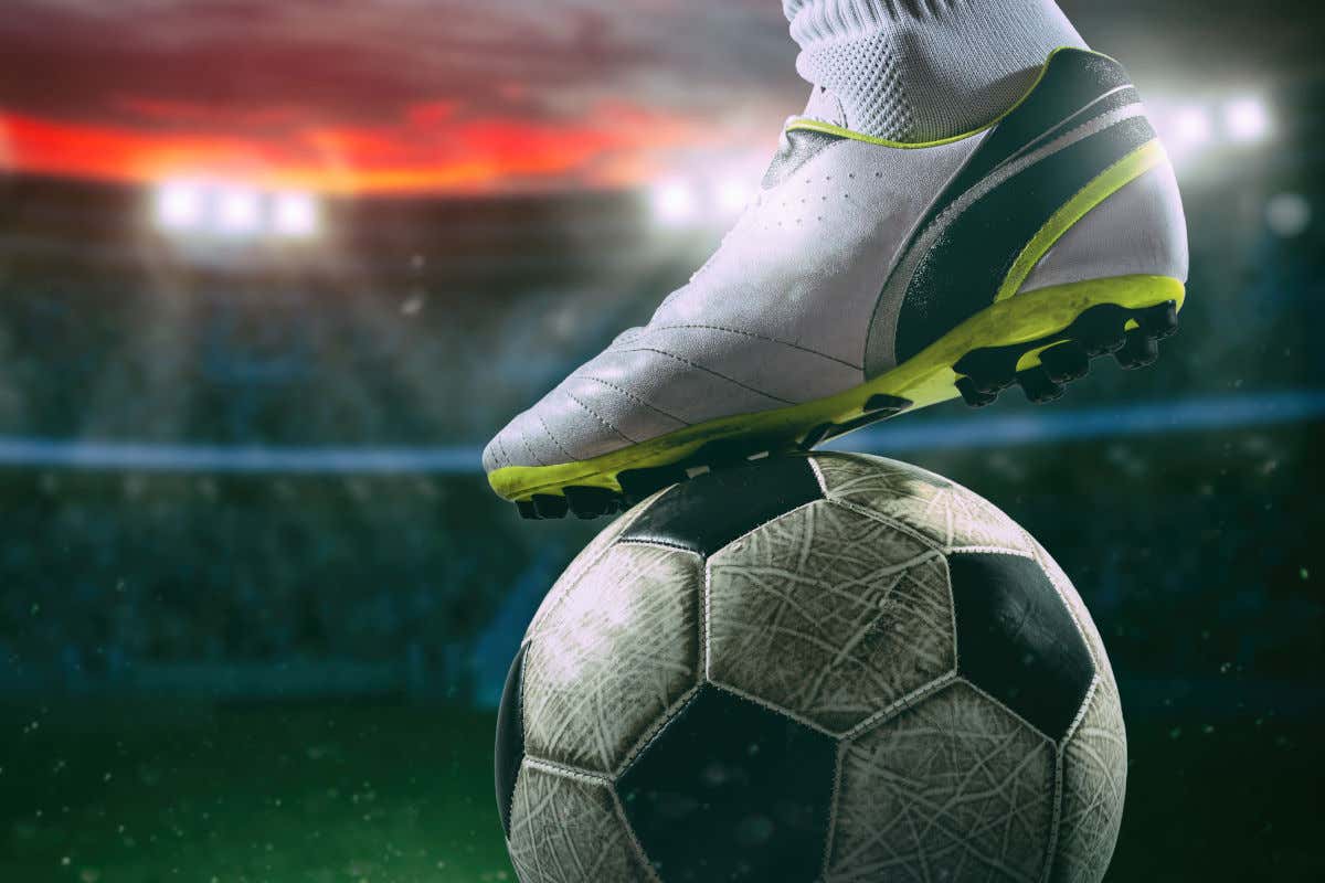 Unas botas de fútbol golpeando un balón en mitad de un estadio