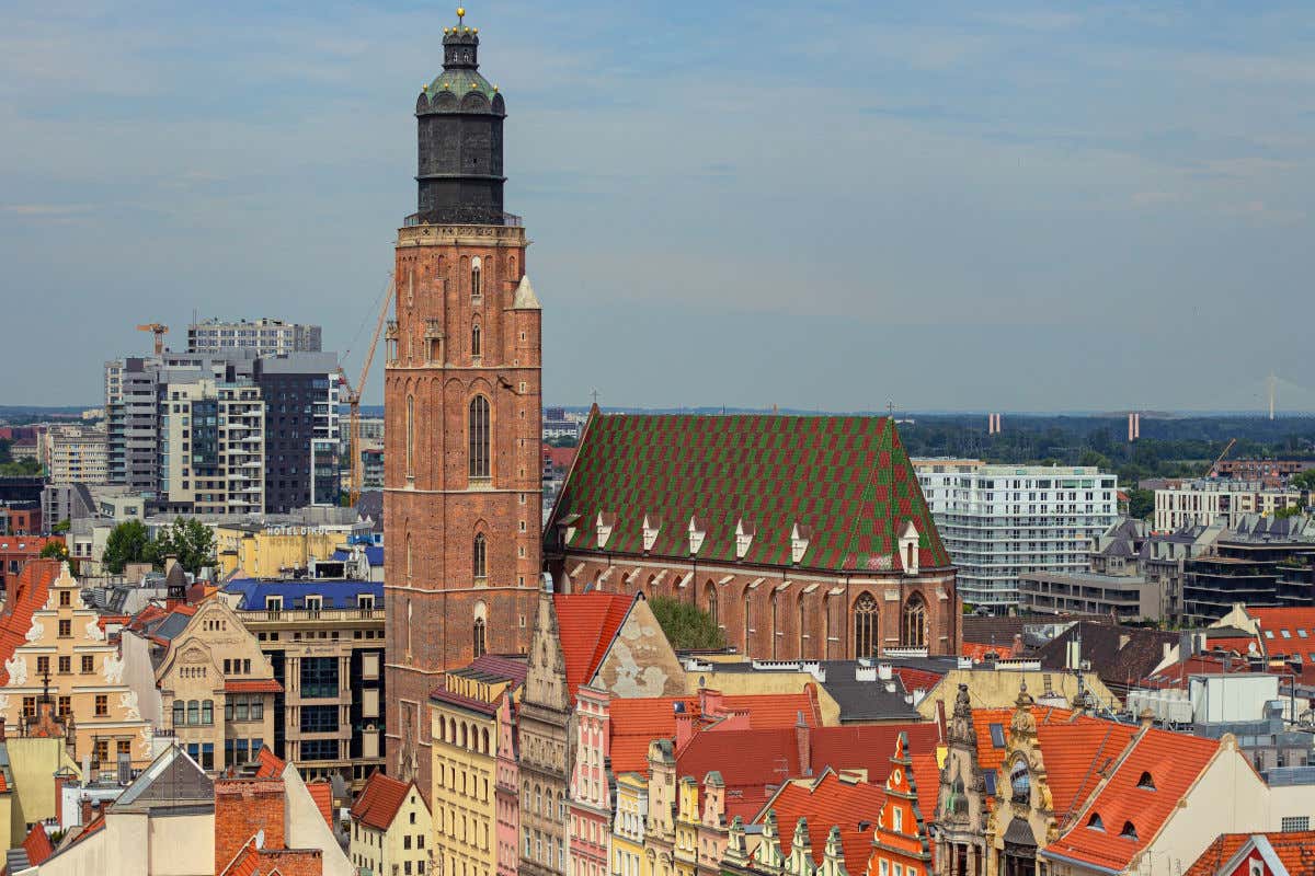 Vista aérea de la basílica de Santa Isabel de Hungría con una gran torre de ladrillo y rodeada de casas de colores pastel