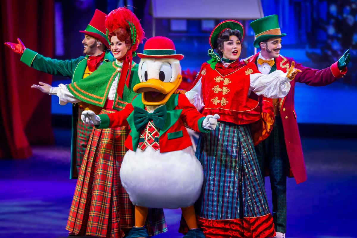 El pato Donald acompañado de varias personas con vestimenta navideña en un espectáculo