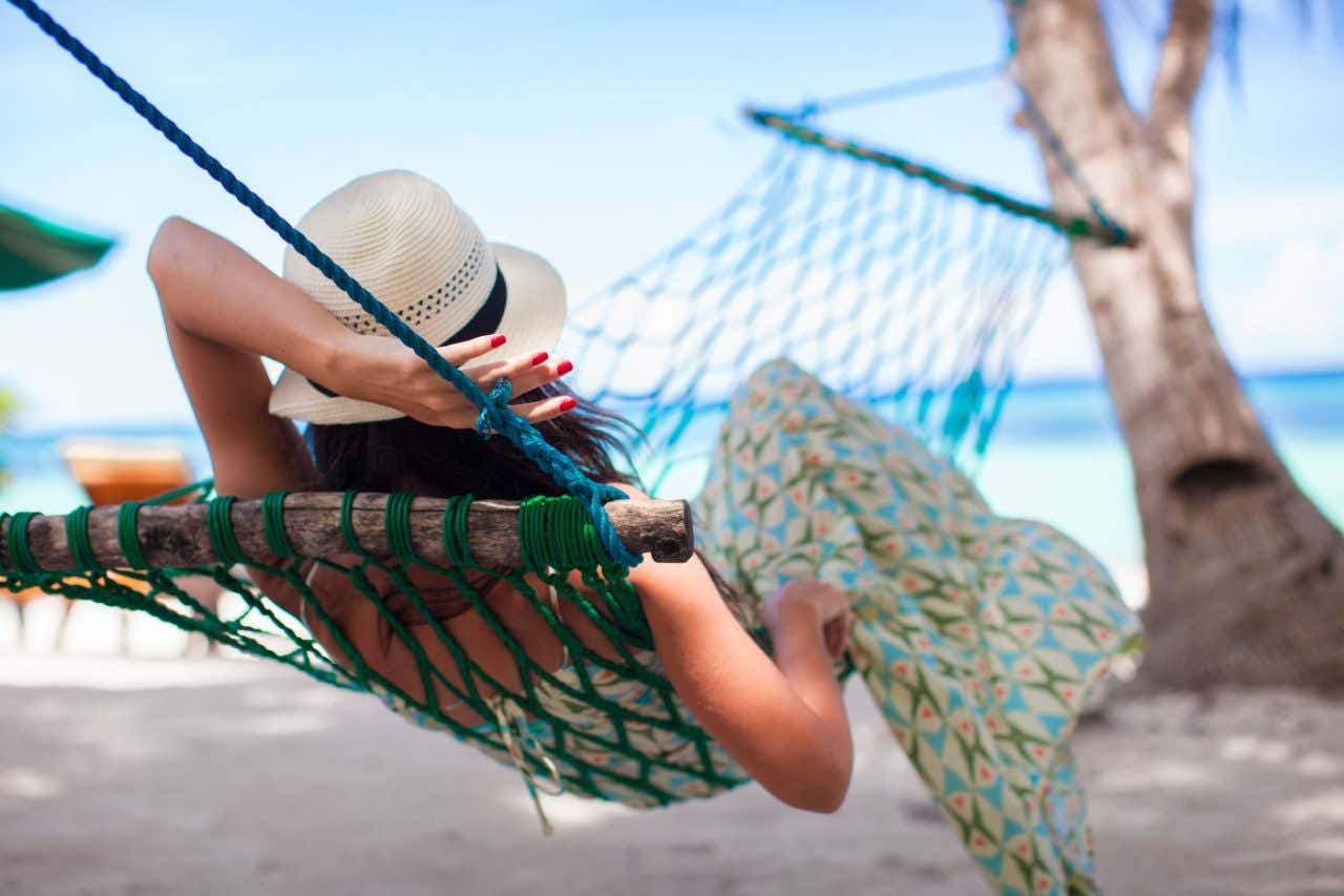 Una mujer tumbada en una hamaca en la playa