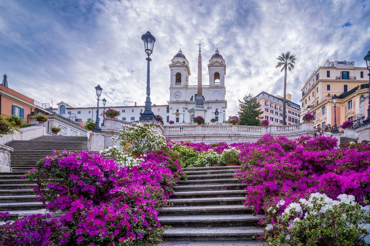 Vista frontal de la escalinata de Piazza Spagna repleta de flores en un día nublado