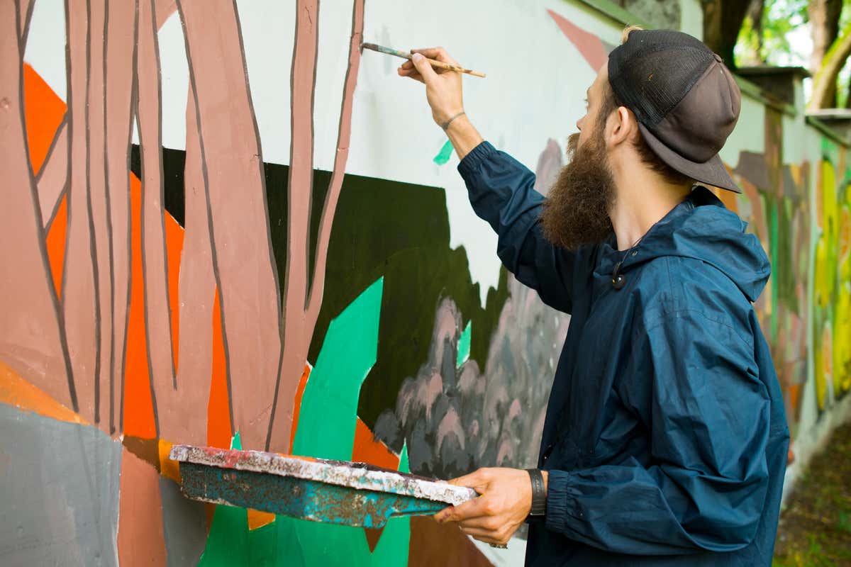 Un artista grafitero pinta un mural de diferentes colores