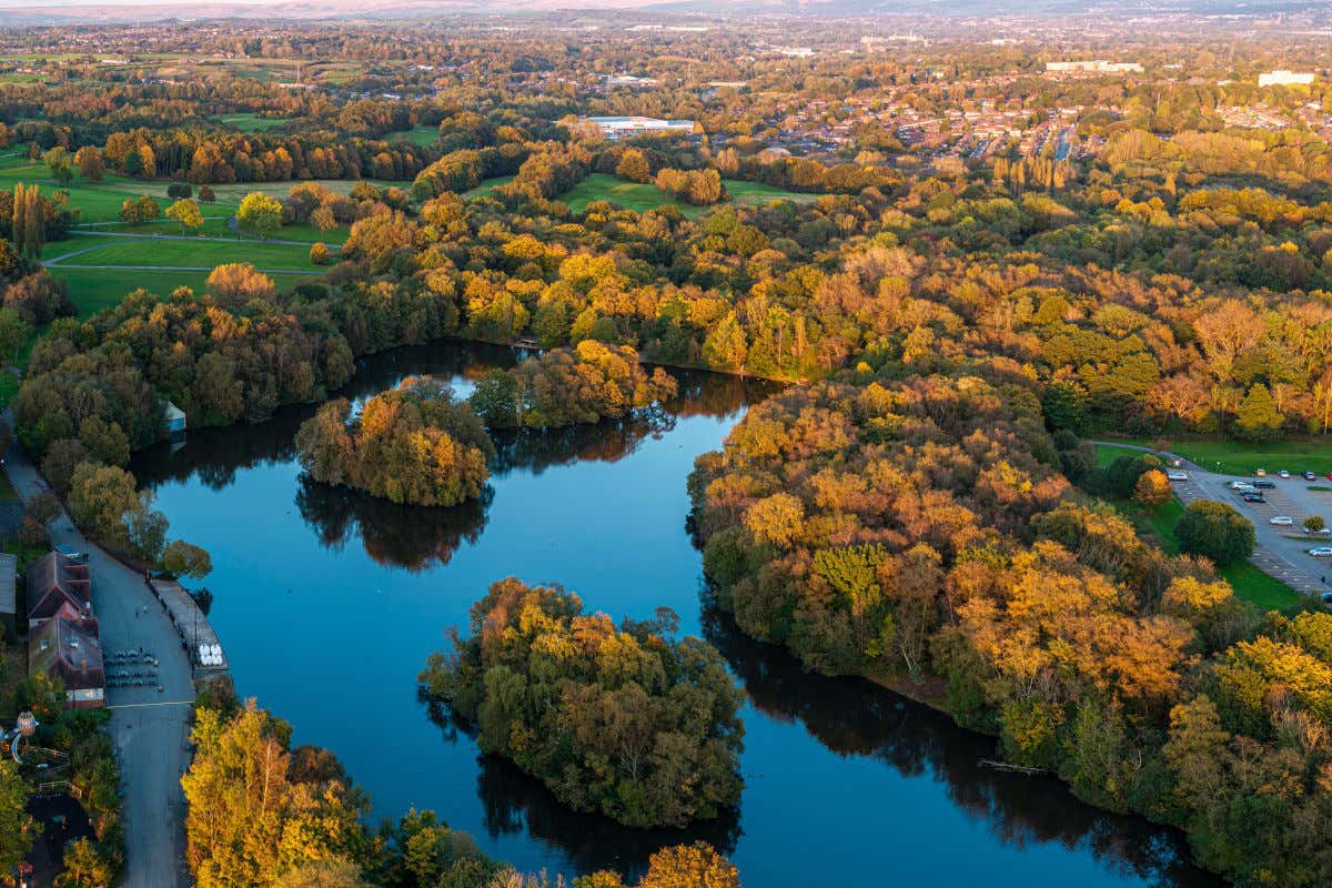 Vista aérea de un parque de Mánchester con muchos árboles y un lago con pequeñas islas