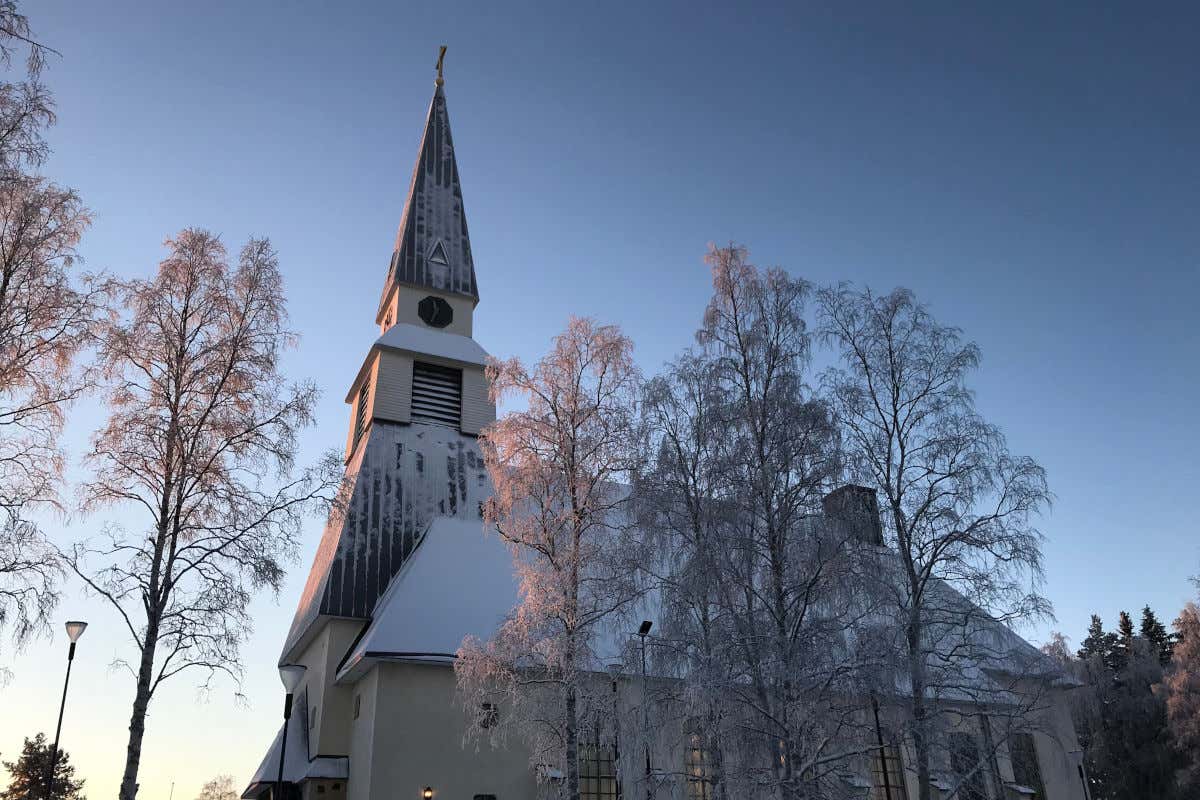 La iglesia de Rovaniemi con su torre y sus tejados nevados en un día despejado