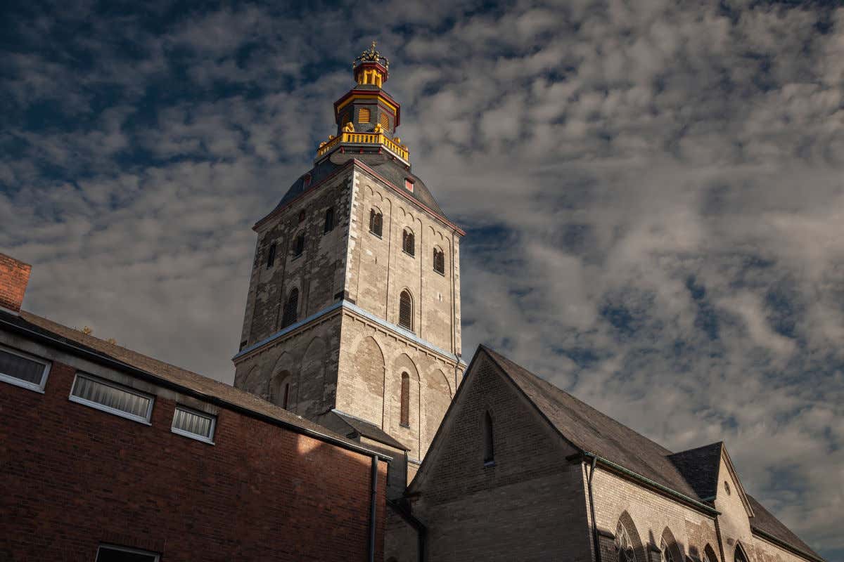 Una iglesia románica con una robusta torre de piedra coronada por un pequeño mirador de decoración dorada