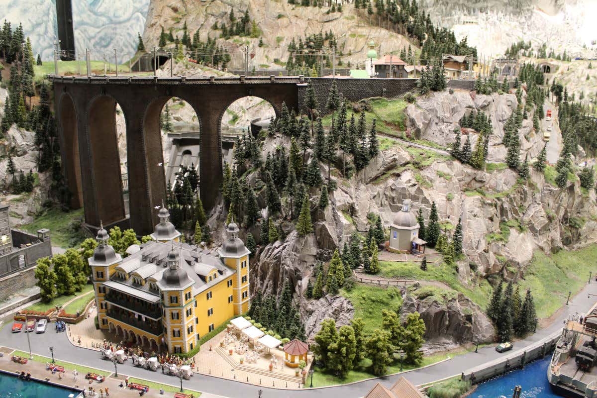 Maquetas de varios edificios y un puente entre montañas en el interior de un museo