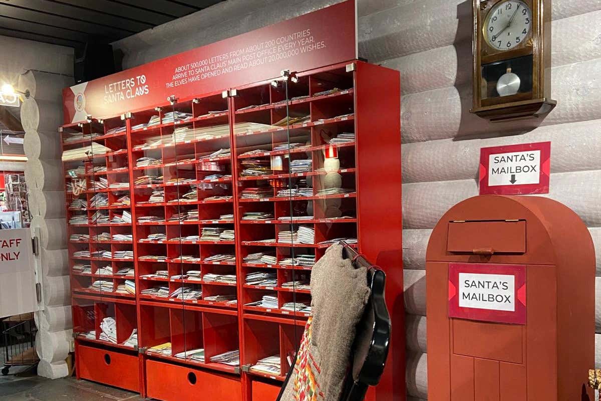 Varias cartas dedicadas a Papá Noel en una estantería roja y junto a un buzón