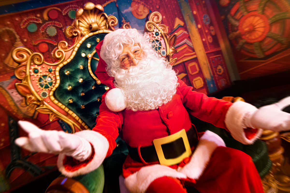 Papá Noel abriendo los brazos en un sillón con decoración de Navidad