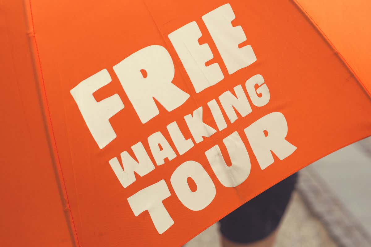 Detalle de un paraguas naranja con unas letras blancas que dicen: Free Walking Tour
