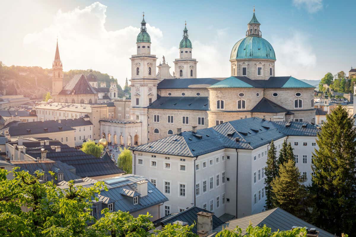 La catedral de Salzburgo con sus dos torres y su cúpula junto a varios edificios de tejados negros en el centro histórico de la ciudad