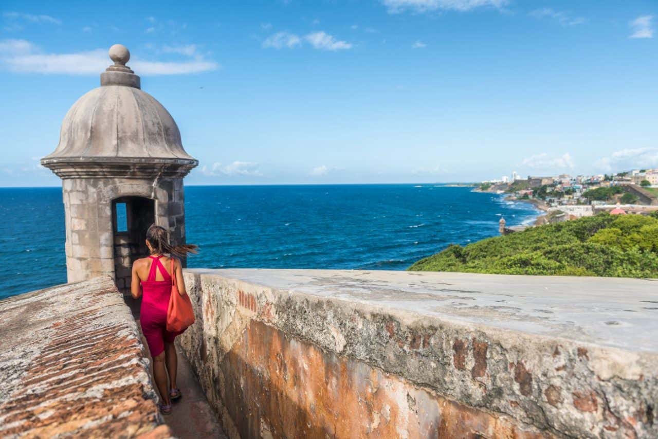 Una mujer camina en un antiguo fuerte con la vista al mar