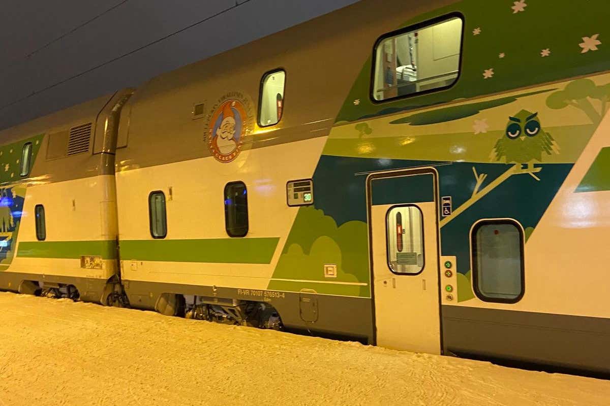 Un tren con el logo de Papá Noel en un andén cubierto de nieve por la noche