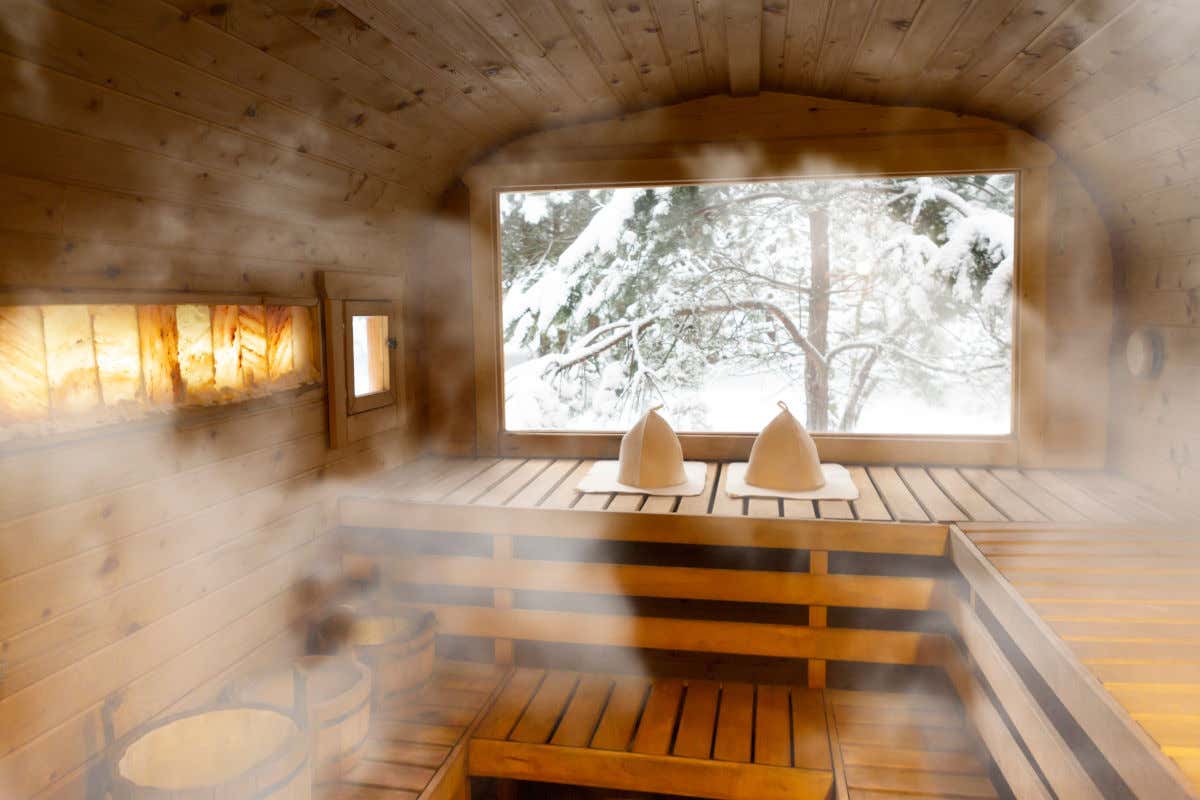 Interior de una sauna finlandesa vacía pero con vistas a los bosques nevados desde una gran ventana