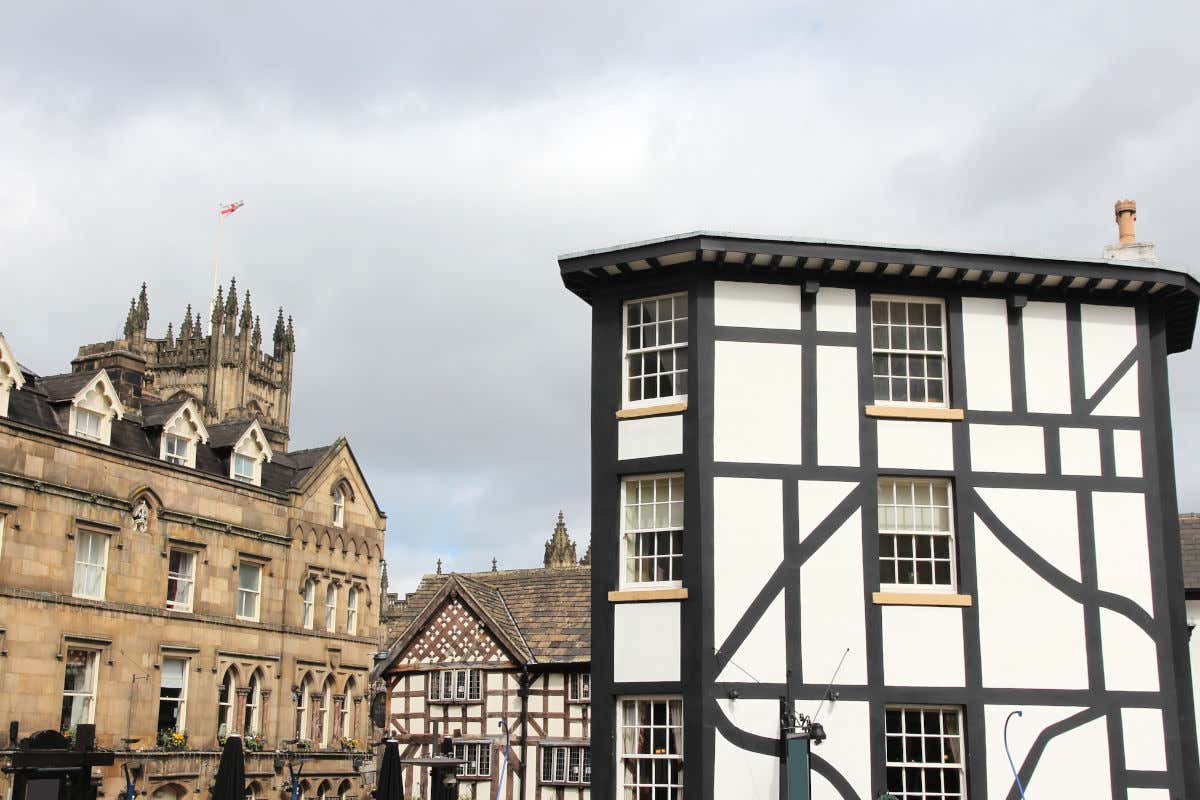 Varias casas medievales con vigas de madera junto a otro edificio antiguo hecho con piedra y la torre de una catedral