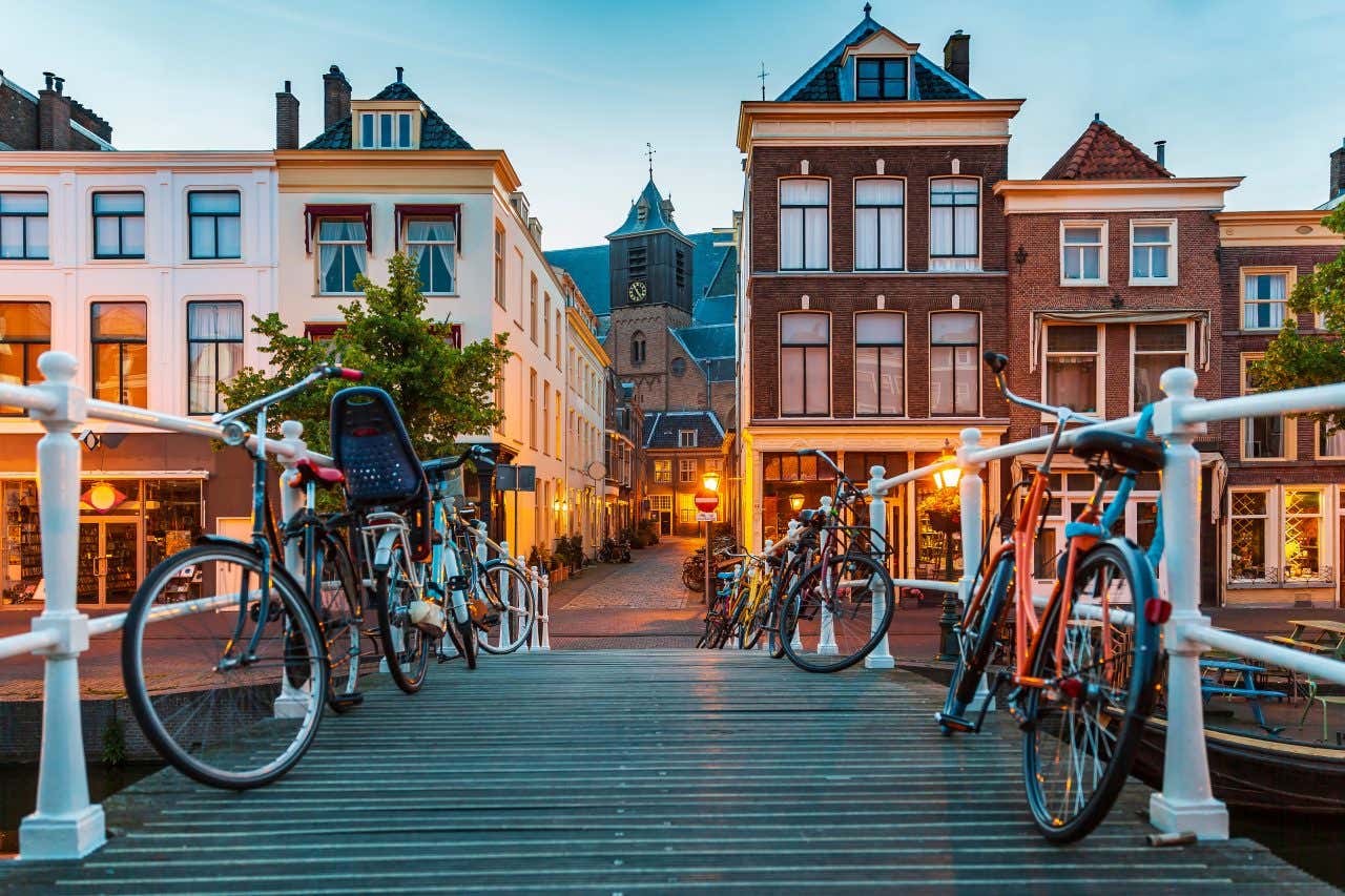 Un ponte su uno dei canali di Amsterdam con biciclette parcheggiate su ambo i lati e palazzi del centro storico sullo sfondo