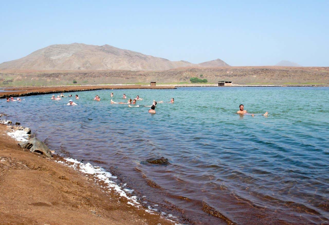 Muitos turistas nadando e flutuando nas piscinas naturais da Pedra de Lume, na Ilha do Sal