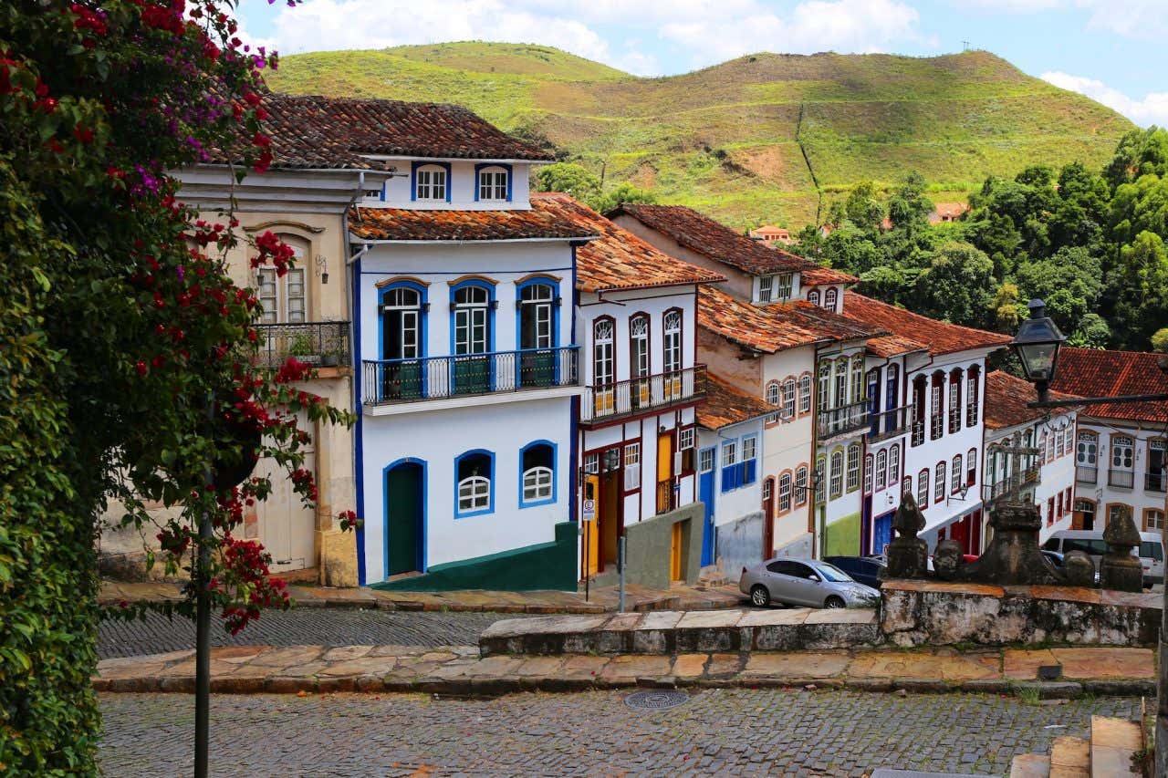 Rua de pedra no centro de Ouro Preto com casarões coloniais coloridos e uma colina ao fundo