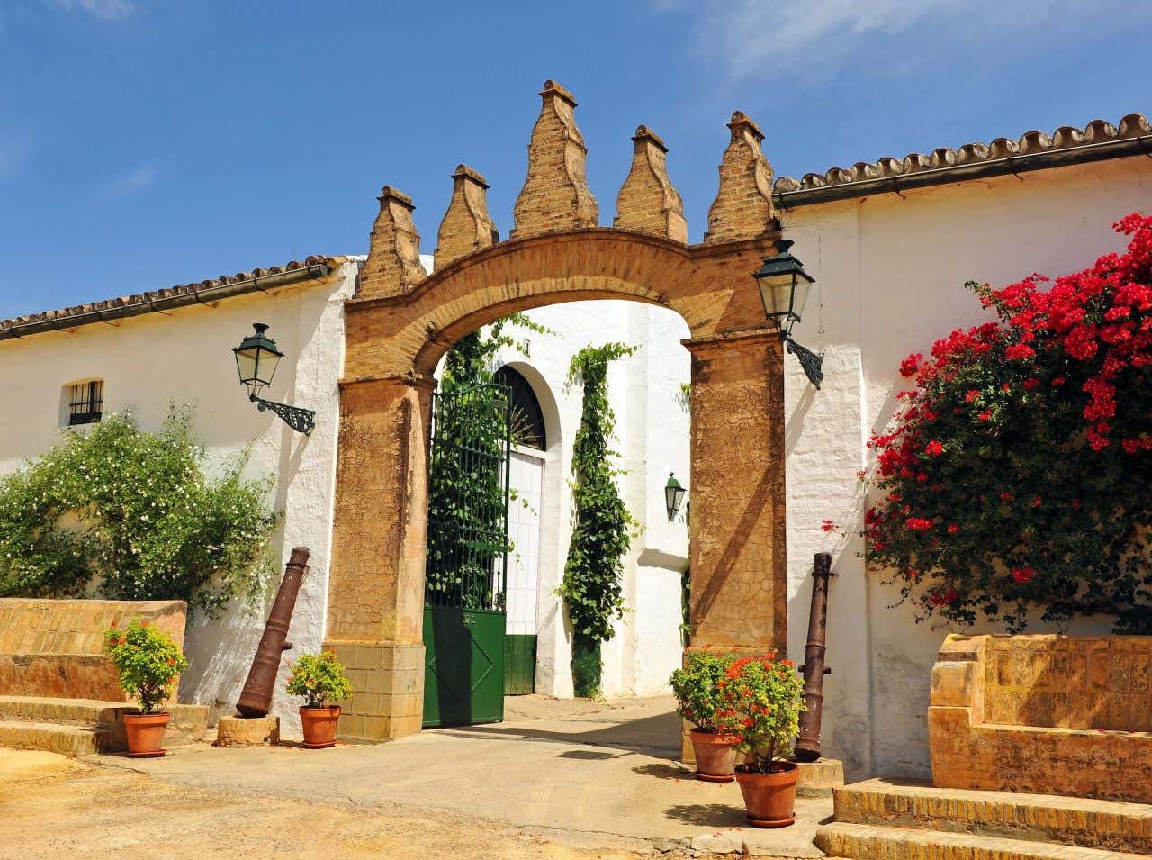 Entrada das Bodegas Góndora com um portal de tijolos à vista e flores ao redor