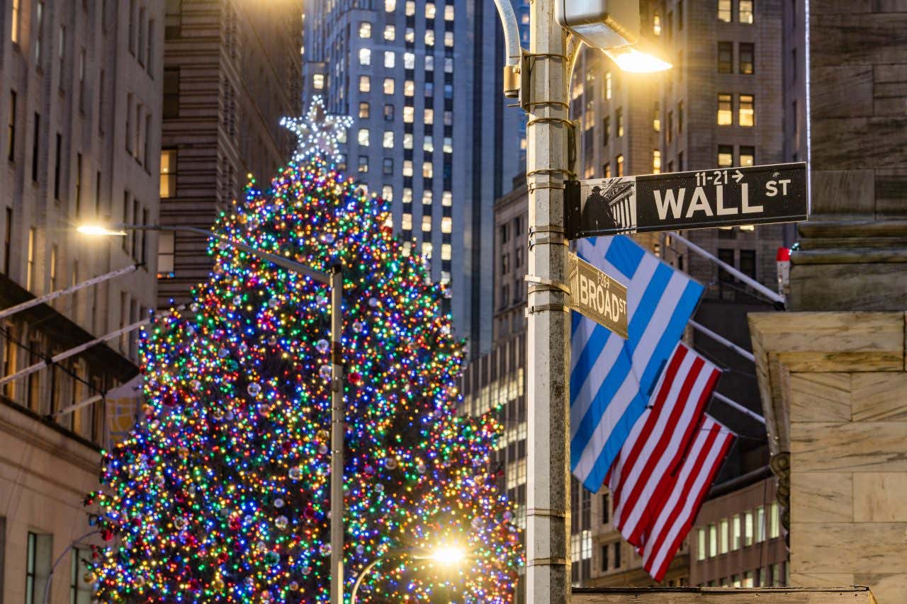 Albero di Natale illuminato con luci colorate a Wall Street, New York, con cartelli stradali e bandiera americana