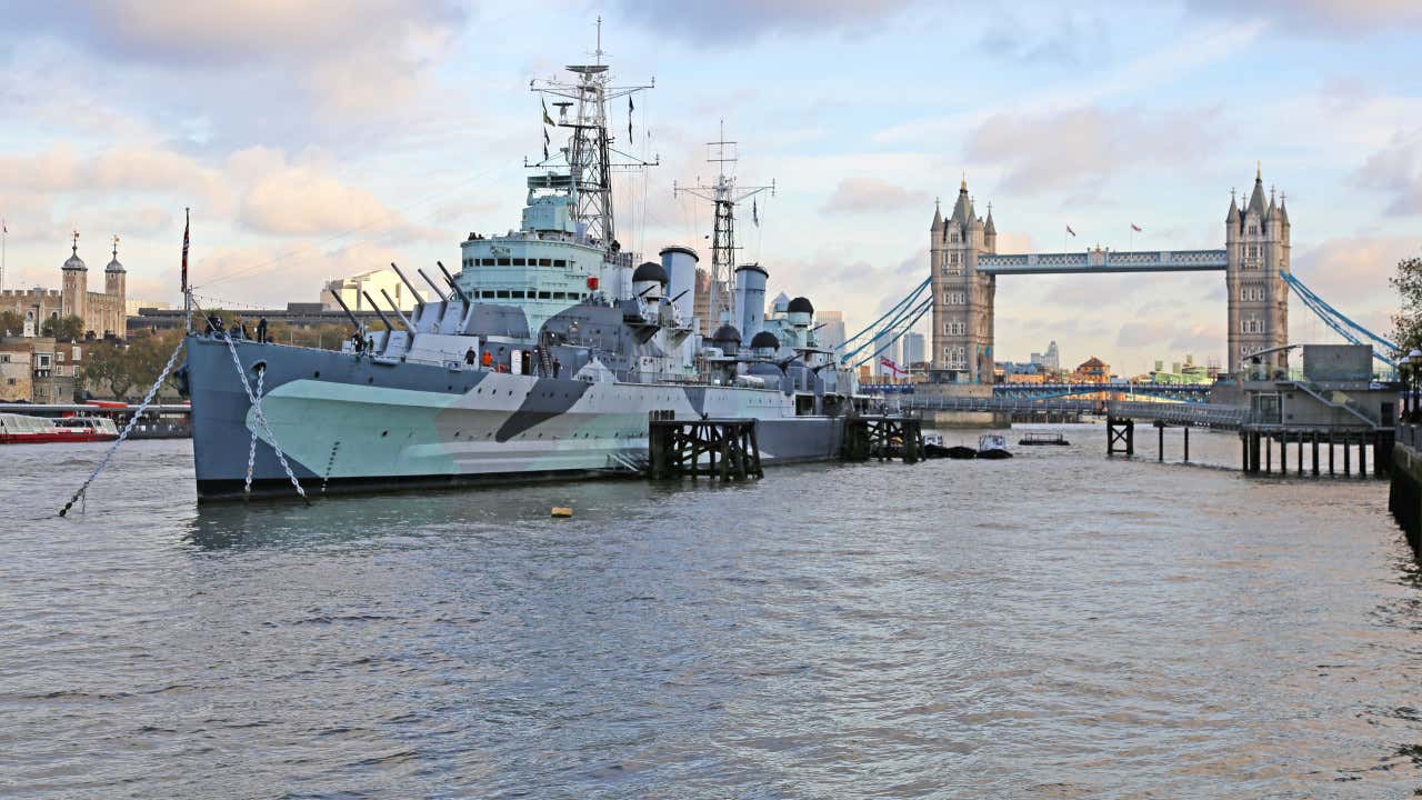 O navio-museu HMS Belfast ancorado no rio Tâmisa com a London Bridge ao fundo
