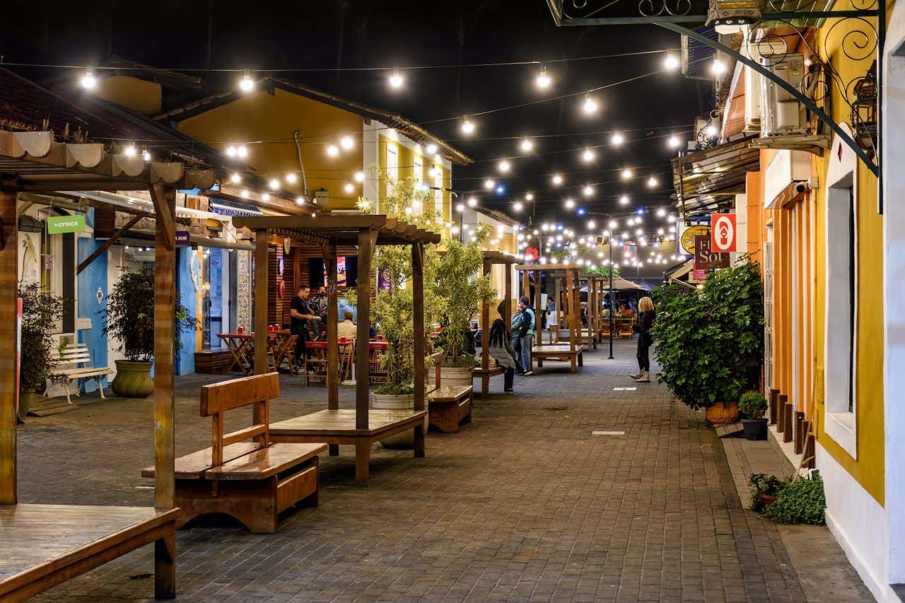 Calçadão de pedestres em Ilhabela à noite com diversos estabelecimentos e iluminação de luzinhas
