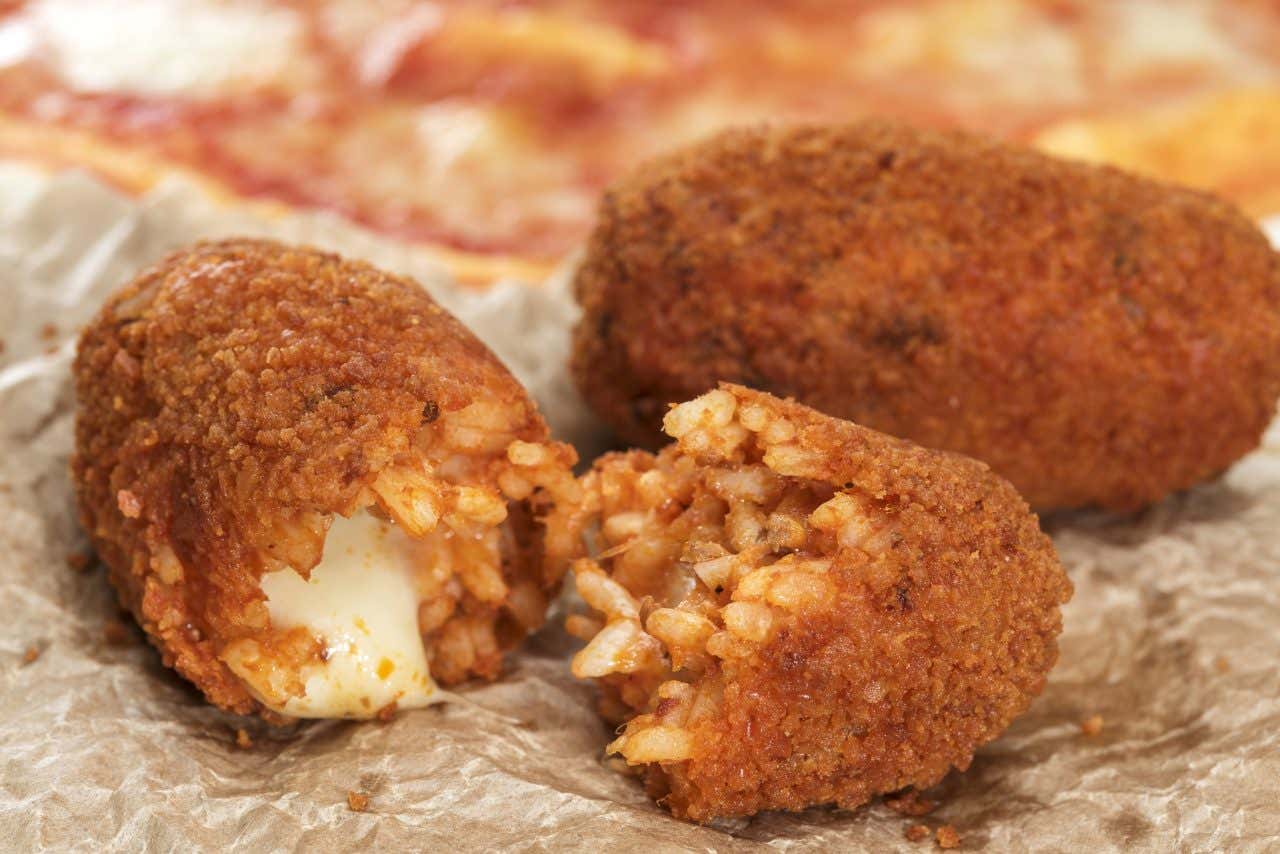 Supplì al telefono romani: crocchette di riso dorate e croccanti con cuore di mozzarella filante, street food tradizionale laziale su carta paglia