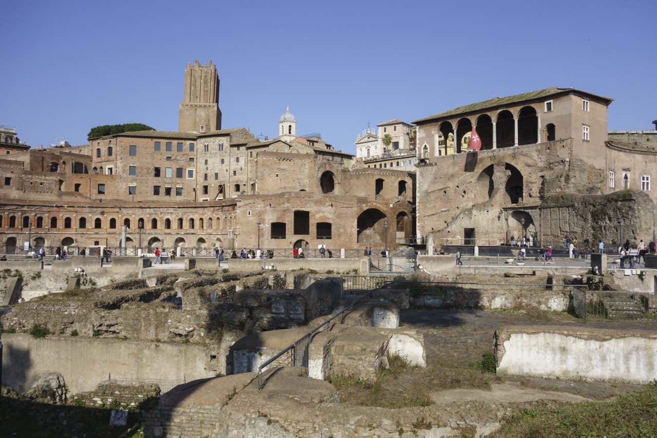Complesso archeologico dei Mercati di Traiano con arcate romane su livelli multipli, Torre delle Milizie medievale sullo sfondo e rovine del Foro di Traiano in primo piano