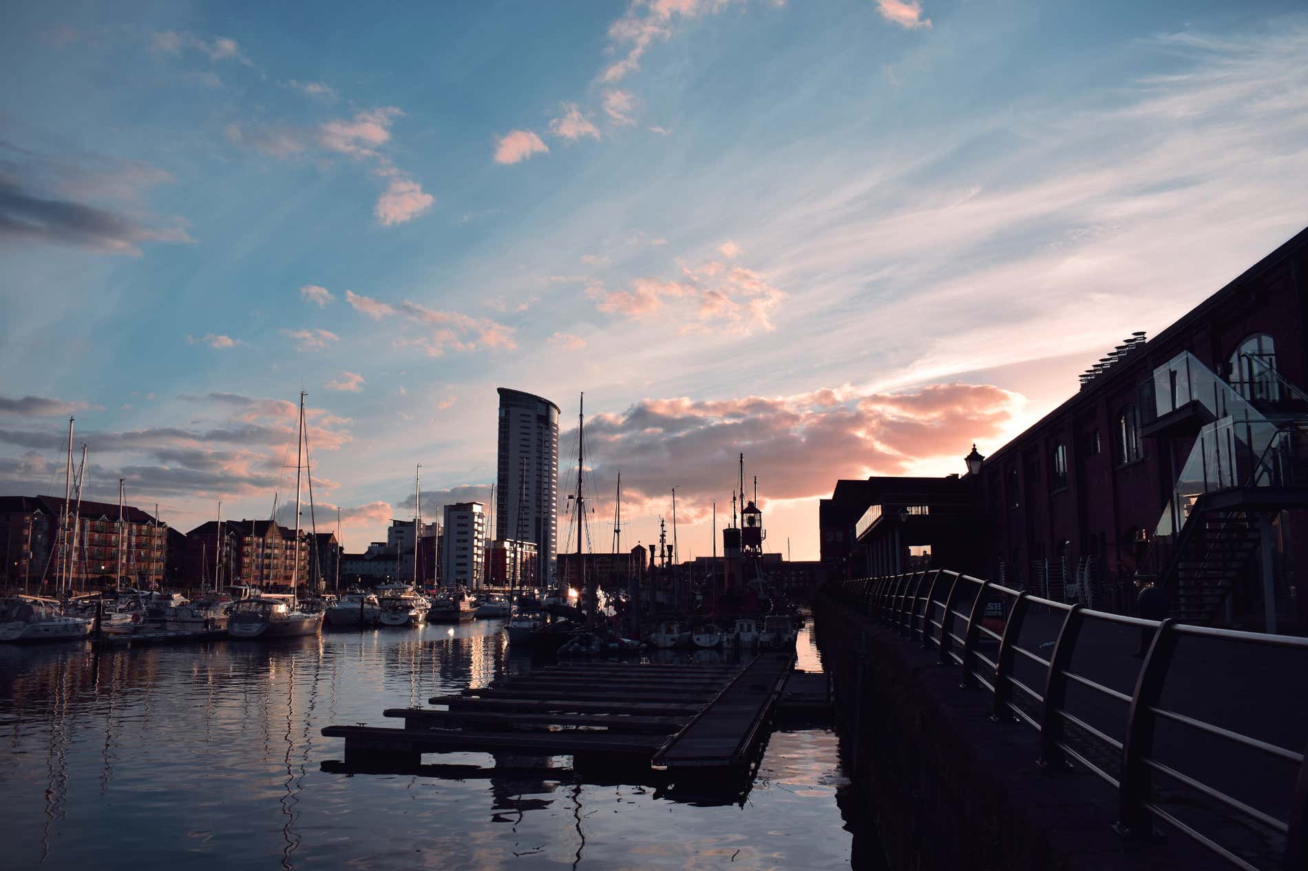 Un piccolo porto al tramonto, con alcune barche illuminate da una luce rosa