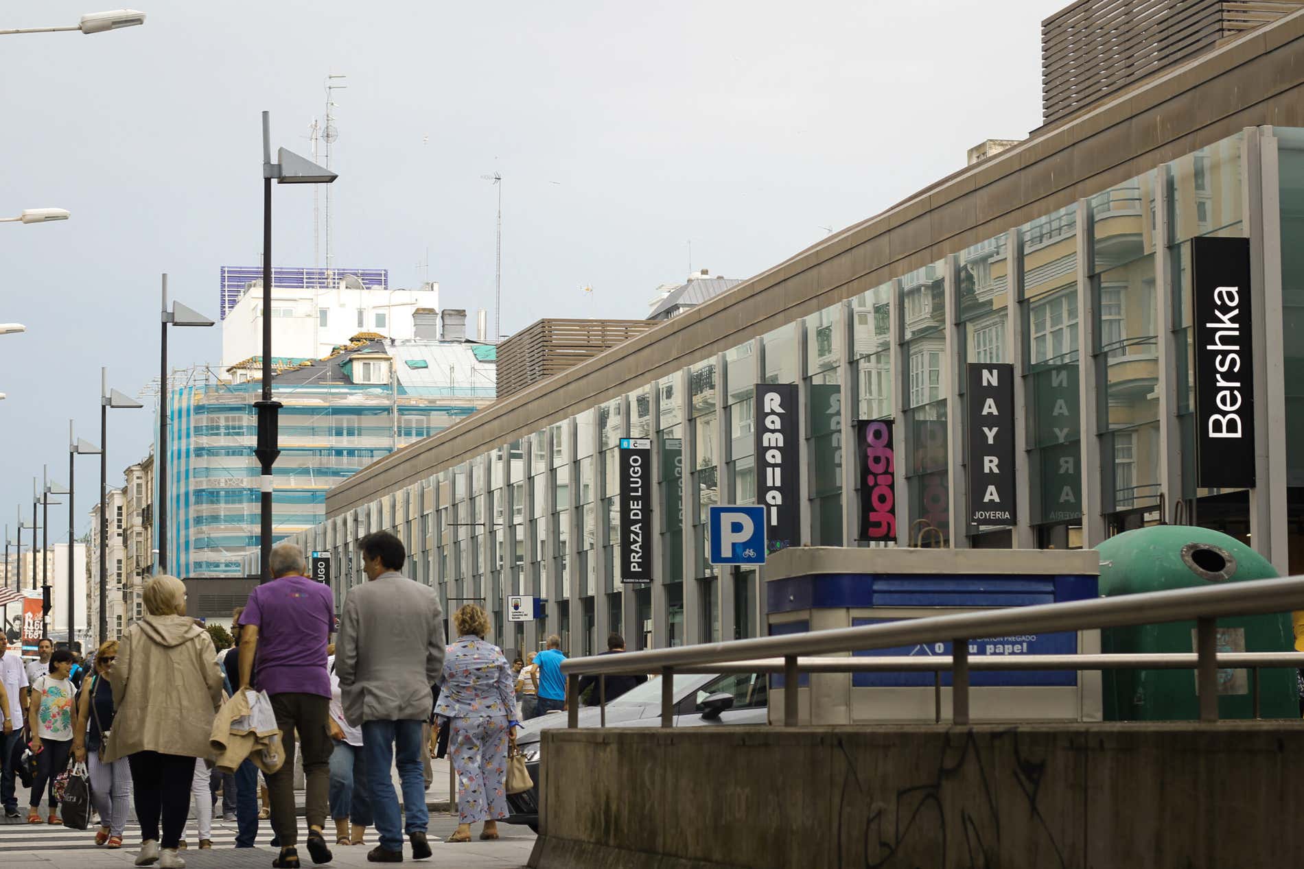 Algumas pessoas caminhando em uma praça comercial de La Coruña em um dia nublado