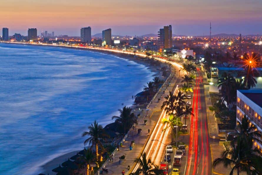 An aerial view of the coastline of Mazatlán, with slow exposure creating lines of light along the coastal road.