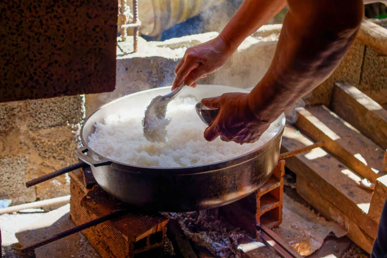 Una persona cocinando arroz en un fogón con bloques