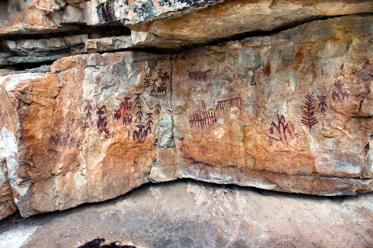 Pinturas rupestres rojas en una cueva de tonos anaranjados
