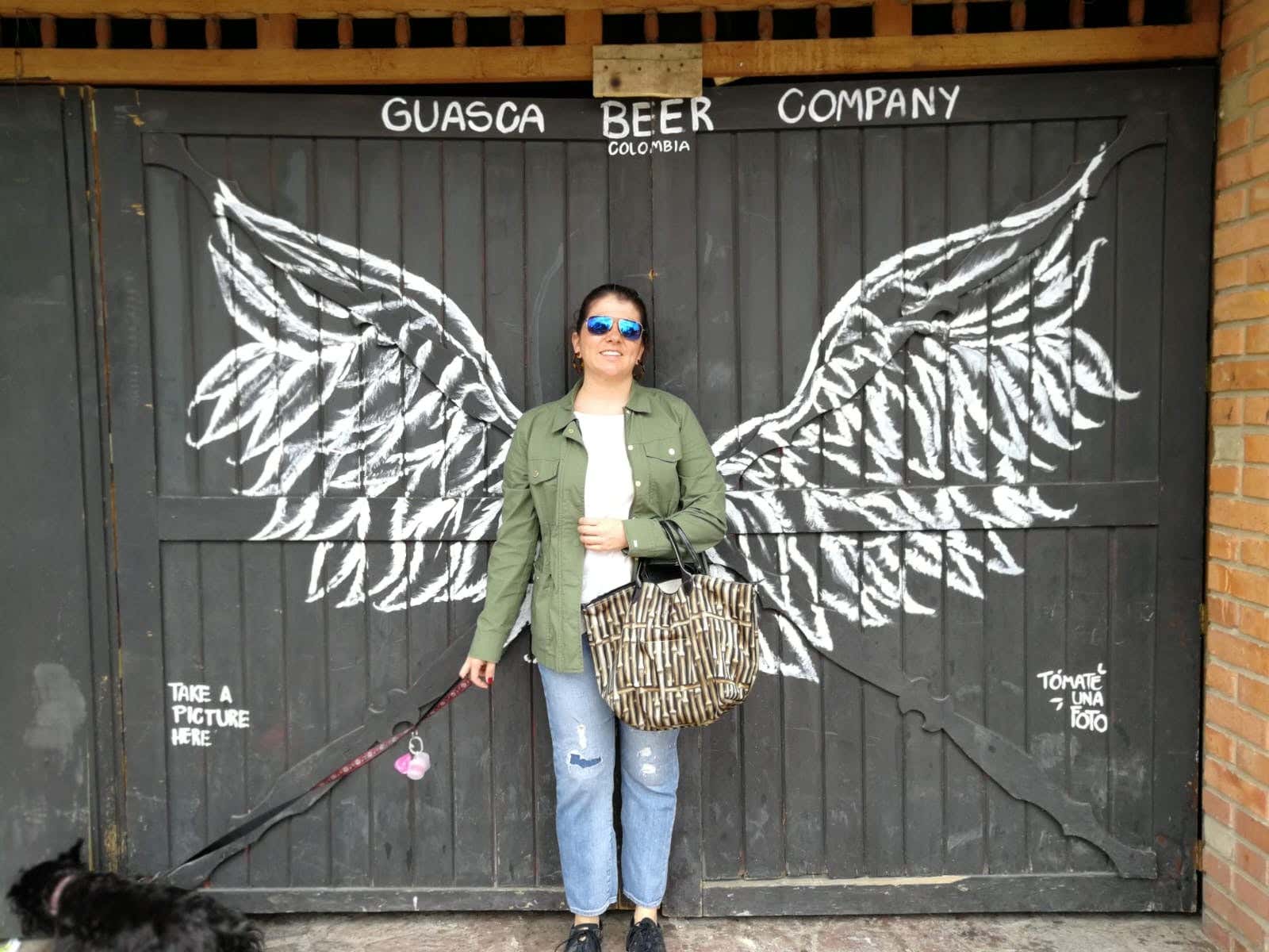 María Carolina posando con unas alas frente a la puerta de Guasca Beer Company, en Colombia