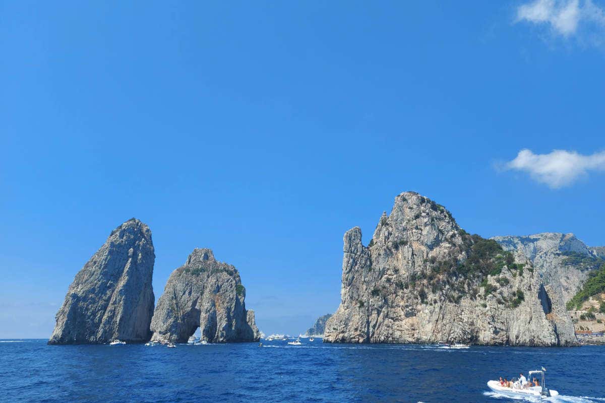 Formaciones rocosas en medio del mar con barcos a su alrededor
